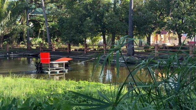 Paddle wheel aerator floating on pond in Chiang Mai