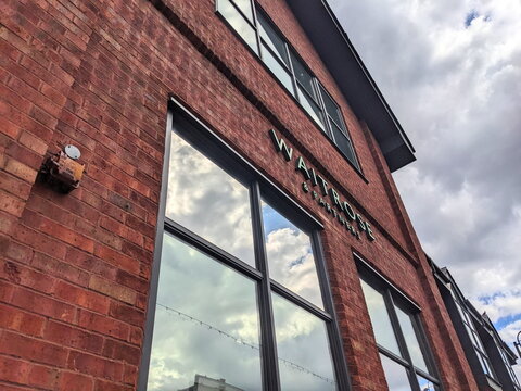 Low angle view of the Waitrose and Partners supermarket red brick facade under a cloudy London sky