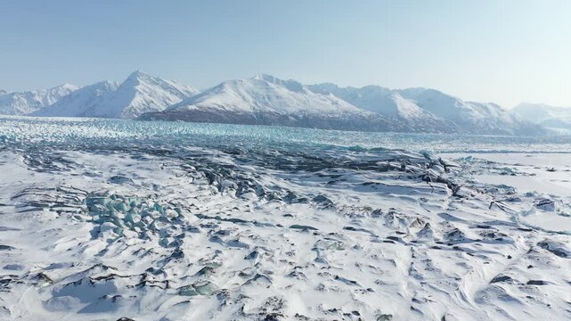 Drone Forward Flyover Above Vast Glacial Ice Field Toward Mountain Range