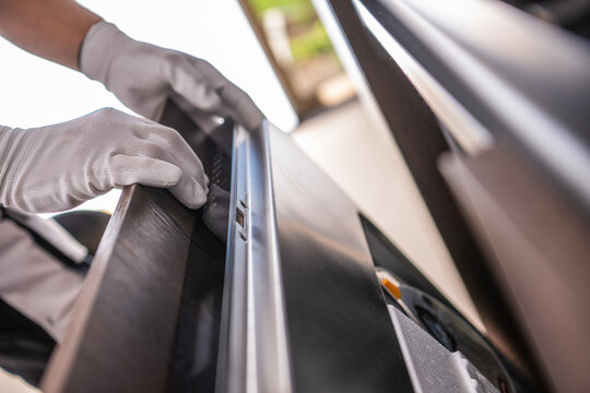 Gloved hands fitting a built-in dishwasher in a new kitchen
