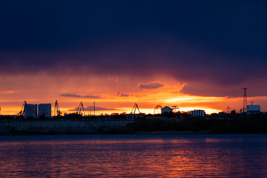 Dramatic sunset over Blagoveshchensk city skyline across Zeya river, capturing vivid sky colors and calm reflective water