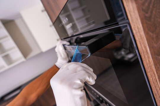 Worker removing protective film from a new built-in oven