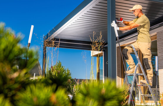 Worker installing a metal pergola from a stepladder