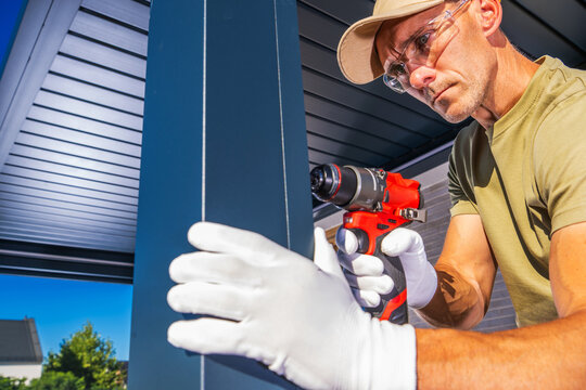 Close-up of a worker drilling into a metal pergola post