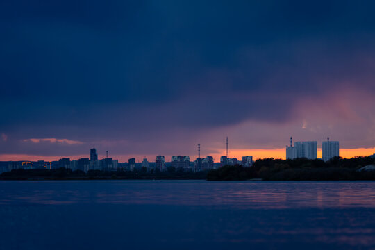 Dramatic sunset over Blagoveshchensk city skyline across Zeya river, capturing vivid sky colors and calm reflective water