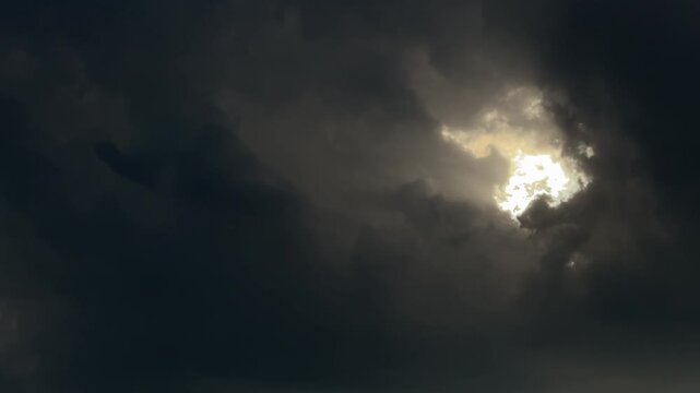 Sunlight shining through dark storm clouds in sky