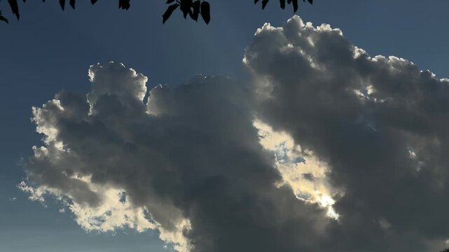 Sunlight shining behind cumulus cloud in blue sky