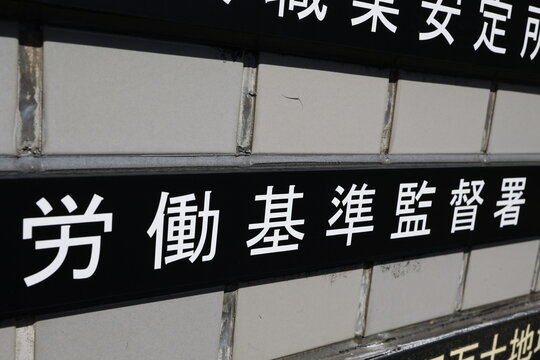 労働基準監督署の看板。タイル壁に映える白文字。