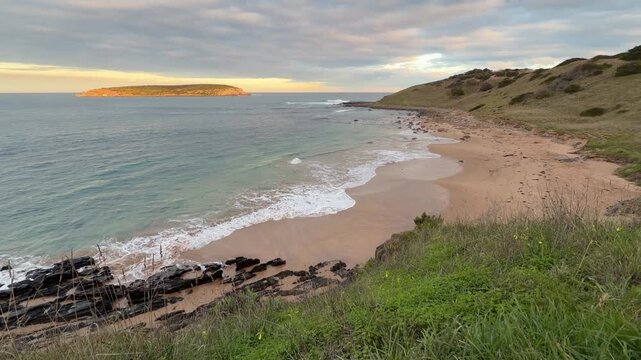 Gentle waves lap at the shore at Kings Beach in South Australia at sunset in 4k footage