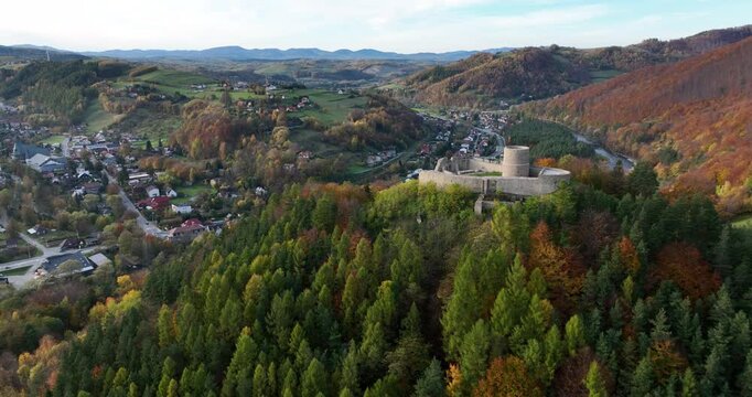 Aerial flyover past Rytro Castle ruins into an autumn river valley