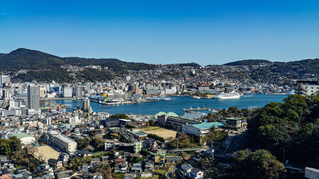Expansive Nagasaki cityscape and Nagasaki Port framed by clear blue sky from Mount Inasa.