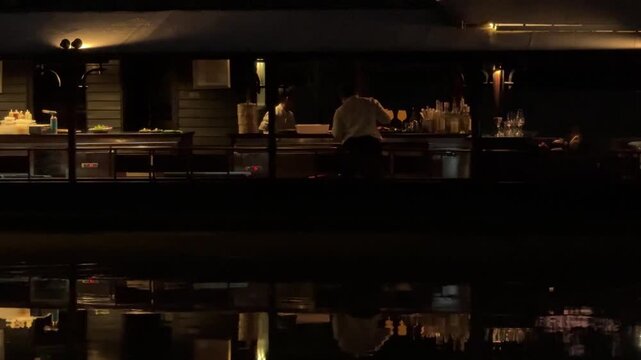 Bartender working on reataurant boat on the Ping river at night in Chiang Mai