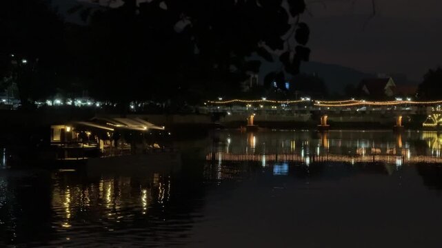 Illuminated bridge reflecting on river at night in Chiang Mai