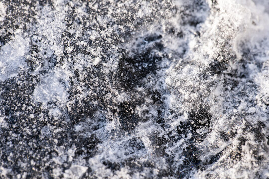 frozen ice under snow. Top View of Snow on Ice Formation with Bubbles Macro Detail of Snow on on Ice Formation with Bubbles Melting Snow on Ice texture and reflection in cold water.Cold weather and