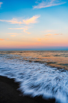 waves crashing on beach with vibrant sky