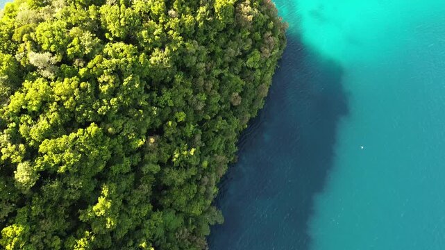 Top-down drone footage flying over jungle-covered rock islands and turquoise lagoon water in Palau