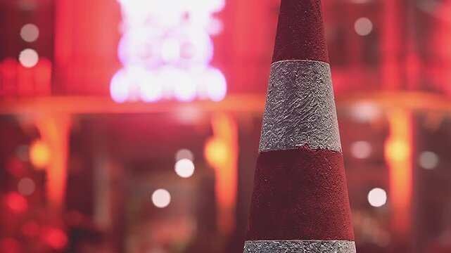 A vibrant traffic cone captures attention amidst the colorful glow of neon lights in a lively urban environment. The scene buzzes with energy and city life at night.