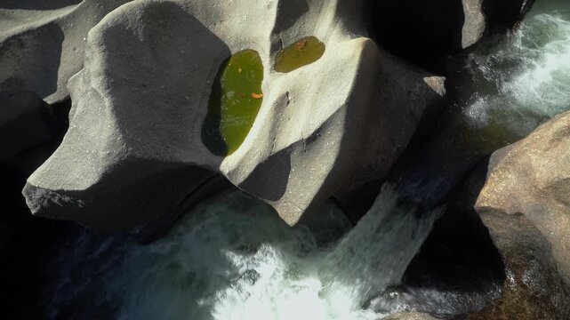 Vale da Lua water stream flows through smooth eroded rock channels along the Sao Miguel River in the Cerrado of Chapada dos Veadeiros, Alto Paraiso de Goias, top down pan follow