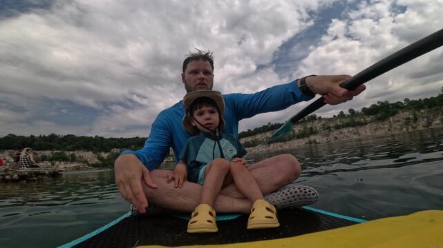 Father and smiling son on a paddleboard outing