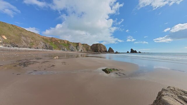 Timelapse panning right beach at low tide ebbing seas blue sky and racing clouds copper Coast waterford Ireland Epic Locations in summer