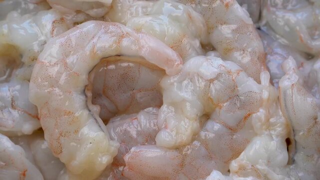 Fresh raw peeled shrimp pile in a rotating zoom out shot