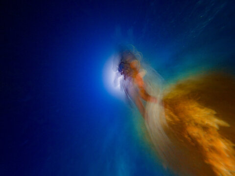Abstract movement photograph of a SCUBA diver underwater at night