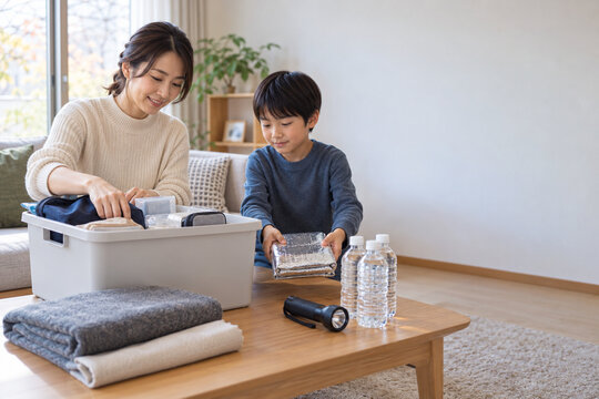 Mother and son organizing a winter emergency kit at home，冬の防災グッズを自宅で整理する母親と息子