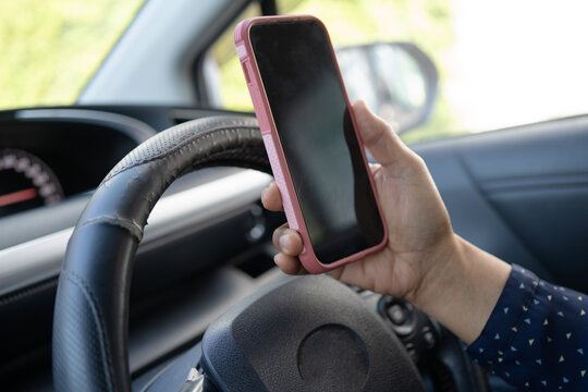 Driver holding mobile phone in car to communication with family and friends.