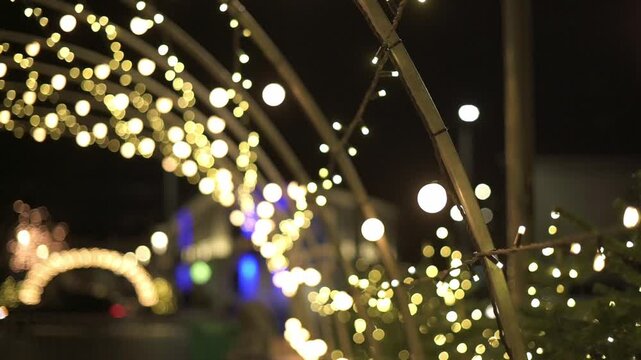 String lights create a vibrant atmosphere in an outdoor setting, with blurred backgrounds and glowing orbs enhancing the festive nighttime scene