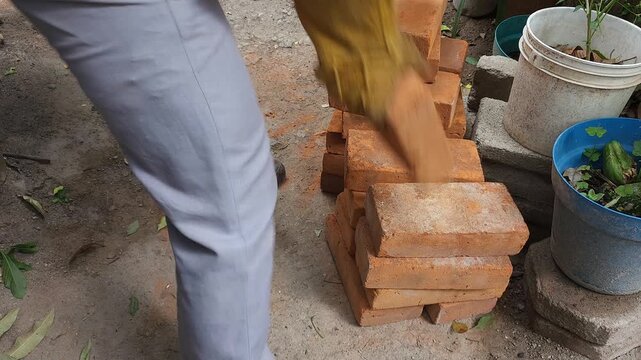 Young Man Carrying and Stacking Clay Bricks at Construction Site