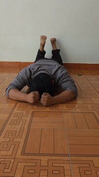 Young Man Lying Face Down Punching Floor in Severe Emotional Distress