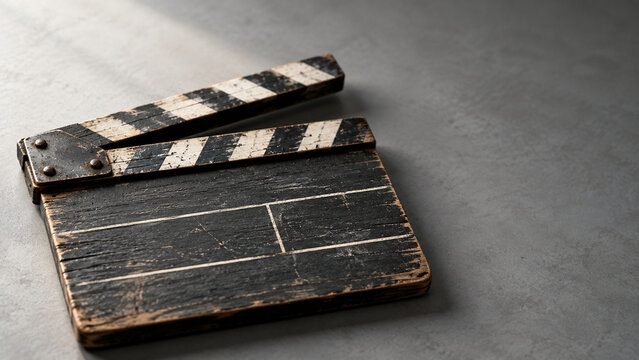 Weathered wooden film clapperboard on grey surface for filmmaking and cinema production concept