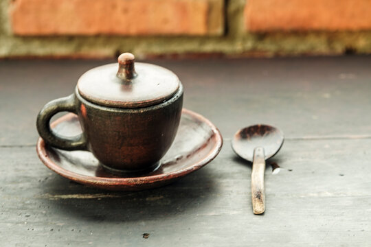 Traditional clay coffee cup with lid and wooden spoon on a rustic wooden table with copy space