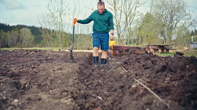 Man Digging A Narrow Trench Into The Soil Using A Shovel In An Open Field - Preparing The Soil In Rows For Planting. - timelapse shot