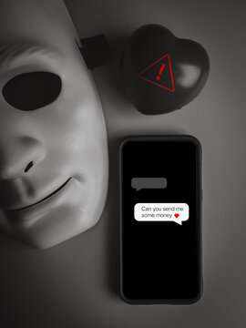 Anonymous mask beside smartphone showing money request message near warning symbol, Romance scams, fake online identities, emotional manipulation, financial fraud and digital deception concepts.