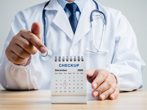 Doctor points to December 2026 desk calendar marked for medical checkup. Year-end preventive healthcare, annual screening, appointment planning and proactive wellness management concepts.