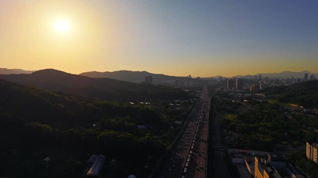 Aerial view flying forward above Gyeongbu Expressway in Seocho gu, Seoul, South Korea, with dense traffic running straight toward hazy skyline and N Seoul Tower at sunset