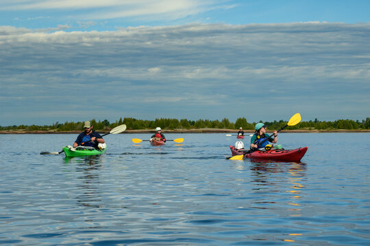 Sea kayakers paddling across a calm bay on a sunny morning, man in green kayak and woman in red kayak leading, blue sky copy space, Georgian Bay, Ontario
