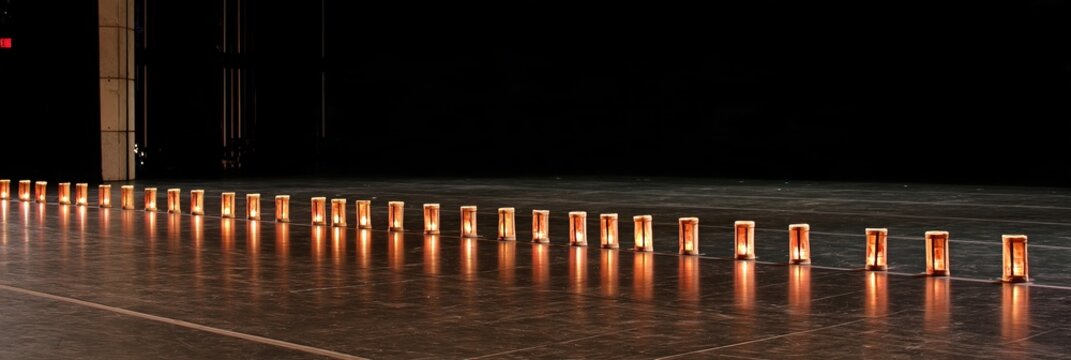 Row of illuminated lanterns on a dark stage floor