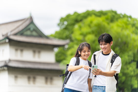 日本の観光地を旅行するアジア人観光客のカップル。インバウンド、観光、名所、スマホ、SNS、口コミ