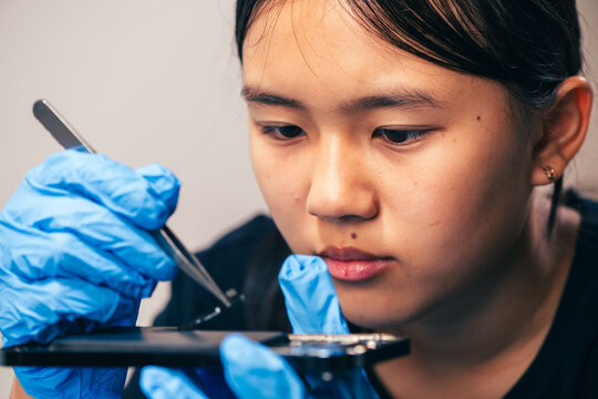 Female technician replaces smartphone lithium battery for hardware repair concept. Conceptual backdrop for phone repair service, right to repair microelectronics, and green circular economy 