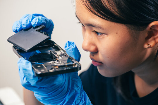 Female technician replaces smartphone lithium battery for hardware repair concept. Conceptual backdrop for phone repair service, right to repair microelectronics, and green circular economy 