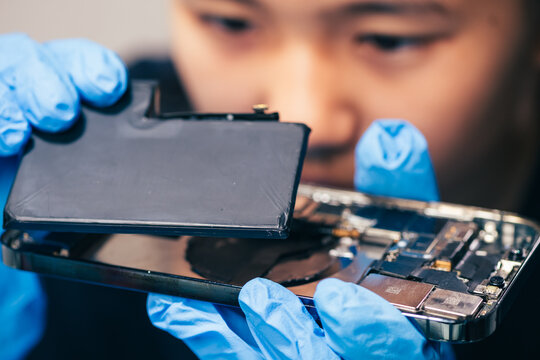 Female technician replaces smartphone lithium battery for hardware repair concept. Conceptual backdrop for phone repair service, right to repair microelectronics, and green circular economy 