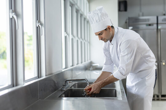 caucasian man chef wash hand in stainless steel sink of commercial kitchen for food preparation hygiene and health safety
