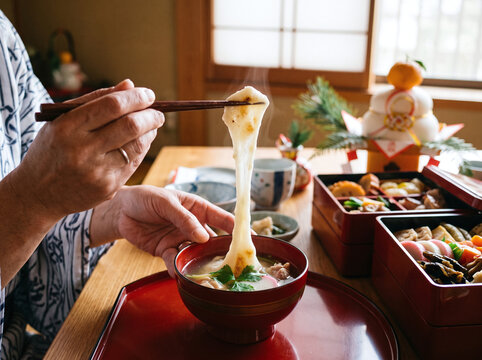 Person stretching hot mochi from traditional ozoni soup on Japanese New Year