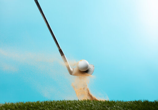 Golf ball explode from Tee off. Golfer hit ball with metal iron club to sand explosion on green. Golf club hit ball on green tee off with sand flying scatter. Blue Sky background isolated