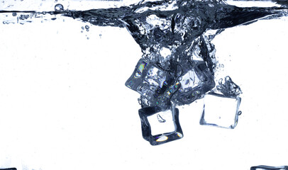 Splashing ice cubes scattered in water creating a dynamic air bubbles motion effect. Isolated white background. Ice Cubes hit water create air bubbles clear drink © Jade
