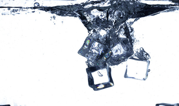 Splashing ice cubes scattered in water creating a dynamic air bubbles motion effect. Isolated white background. Ice Cubes hit water create air bubbles clear drink
