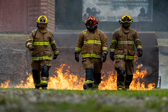 Team of firefighter in fireproof clothe walking out of the burning building full of ash and smoke for fire extinguish risk rescue mission and accident management