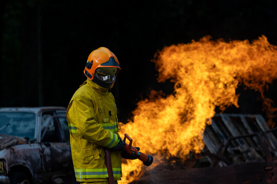 Team of firefighter in fireproof clothe with oxygen tank using twirl fog watering hose to put out the burning building with high flame for fire extinguish risk rescue mission and accident management